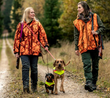 2 Jägerinnen mit ihren Jagdhunden auf einem Waldweg.